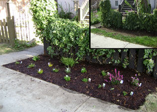 (a bed in front of a fence by a sidewalk)