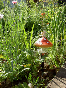 (a section of garden with a squirrel-and-mushroom ornament)